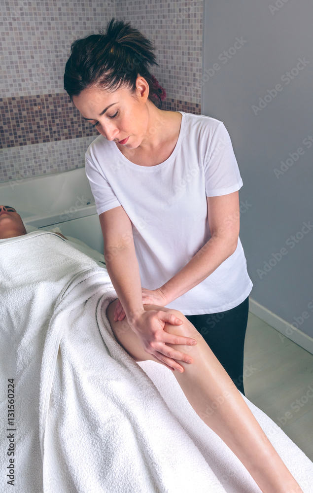 Portrait of female massage therapist doing lymphatic drainage massage on legs of young woman in a clinical center. Medicine, healthcare and beauty concept.
