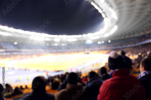 Fans watching football game at stadium, blurred background