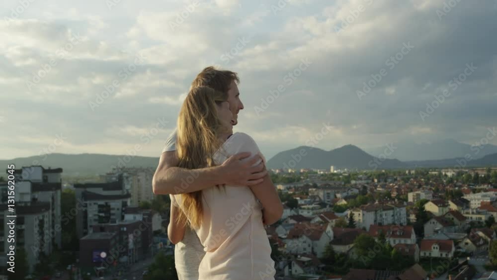 CLOSE UP: Boyfriend and girlfriend standing on the edge of skyscraper hugging CLOSE UP: Boyfriend and girlfriend standing on the edge of skyscraper hugging