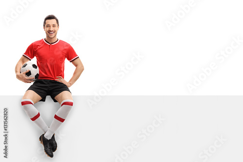 Fototapeta Naklejka Na Ścianę i Meble -  Happy football player sitting on a panel