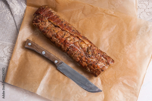 Smoked meat or ham and knife on brown packing paper.