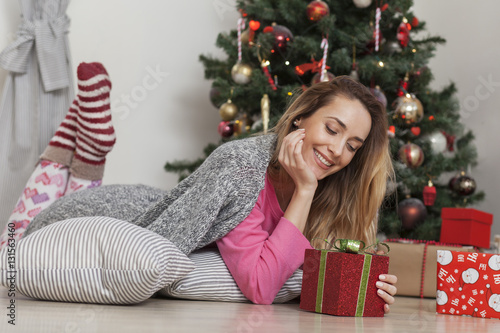 Beautiful woman with christmas box gift in front of Christmas tree