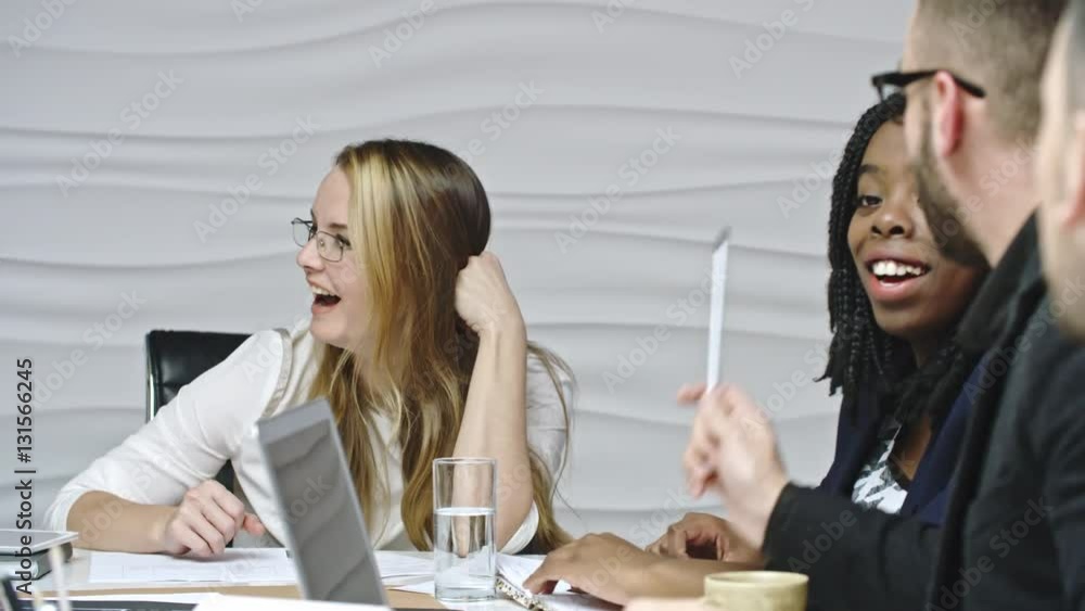 Young energetic business people smiling and laughing while discussing something at meeting Young energetic business people smiling and laughing while discussing something at meeting