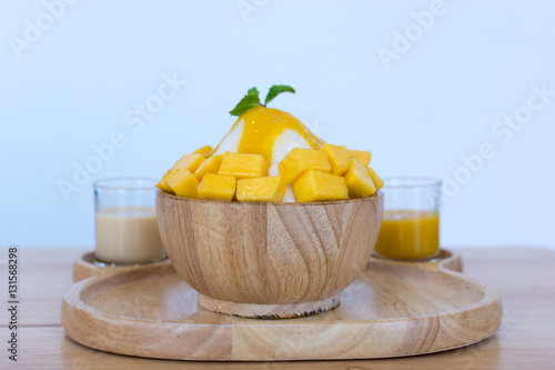 Bingsu ( Korea food) mango served with sweetened condensed milk on table