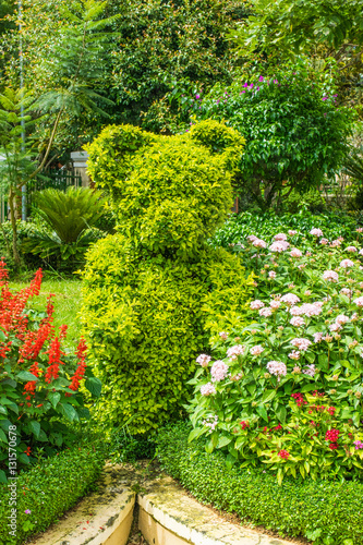 Landscape design - green figure of bear between flowers