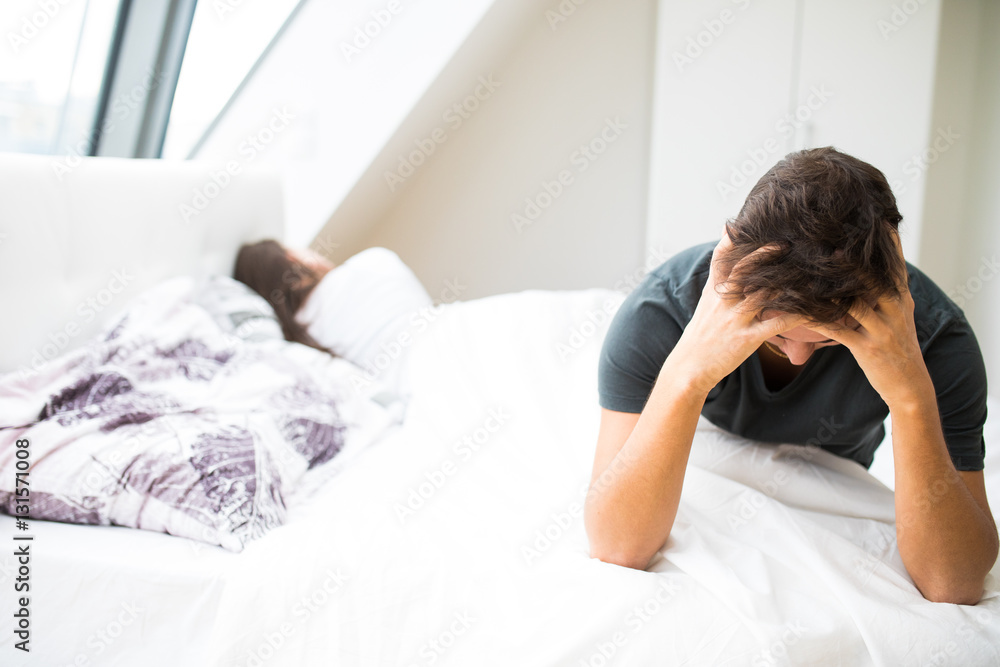 Portrait of unhappy young heterosexual couple in bedroom