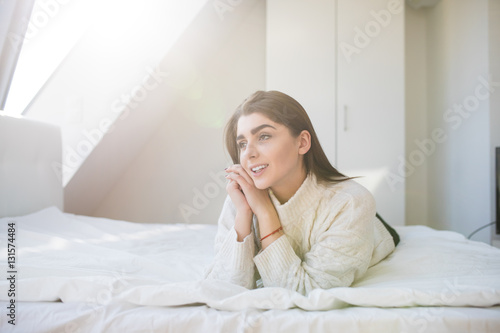 Happy woman lying on the bed and waking up in the morning