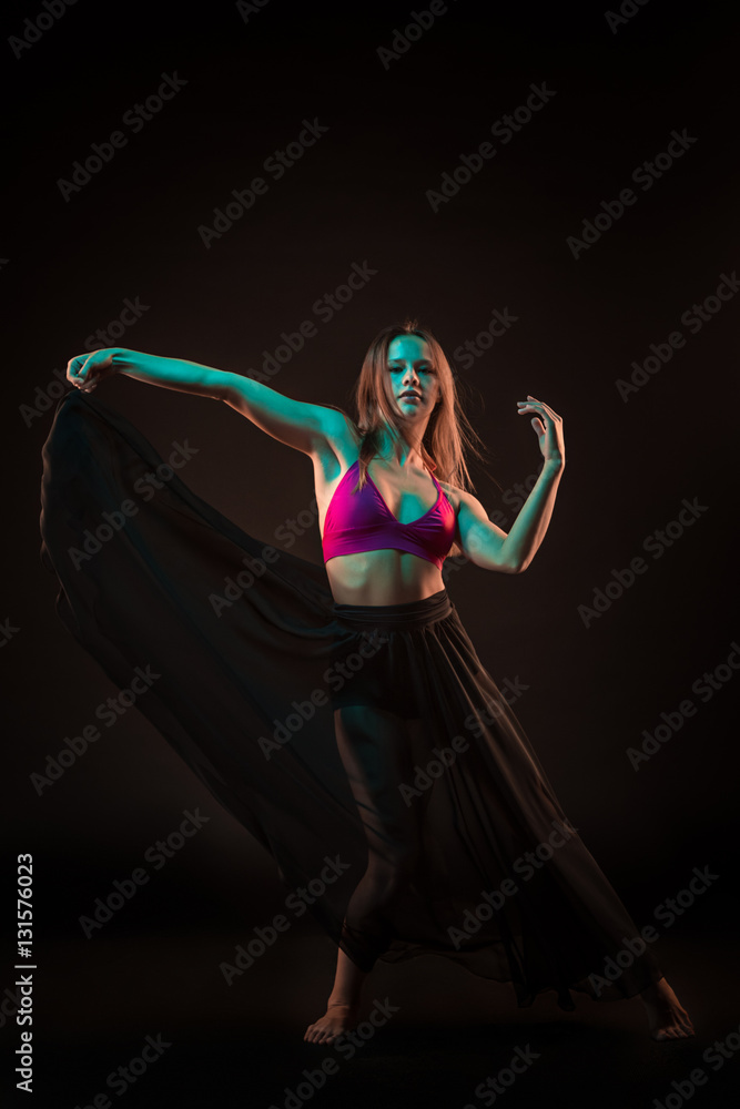 Young beautiful dancer in beige dress dancing on black background Young beautiful dancer in beige dress dancing on black background