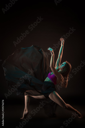 Fototapeta Naklejka Na Ścianę i Meble -  Young beautiful dancer in beige dress dancing on black background