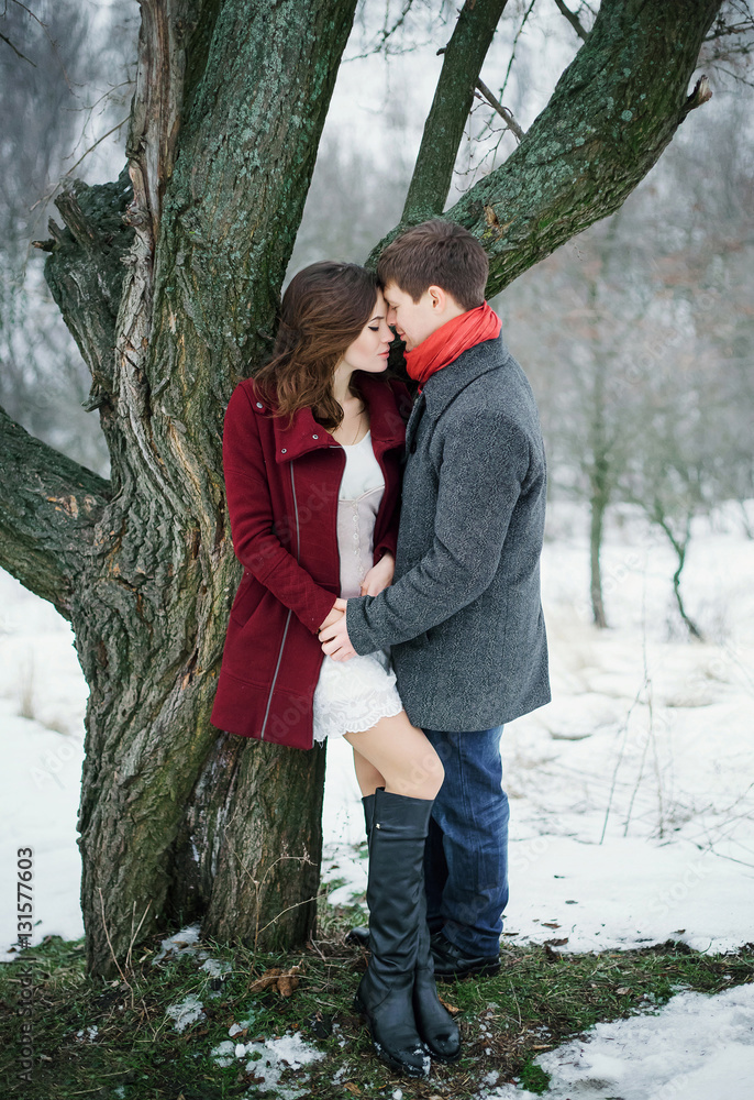 Man gently holds hand of a beautiful girl. They stand at great tree. Love of two hearts. Scenic winter walk in Park. A romantic feeling. Fantastic shooting. Fashionable toning. Creative color. Man gently holds hand of a beautiful girl. They stand at great tree. Love of two hearts. Scenic winter walk in Park. A romantic feeling. Fantastic shooting. Fashionable toning. Creative color.