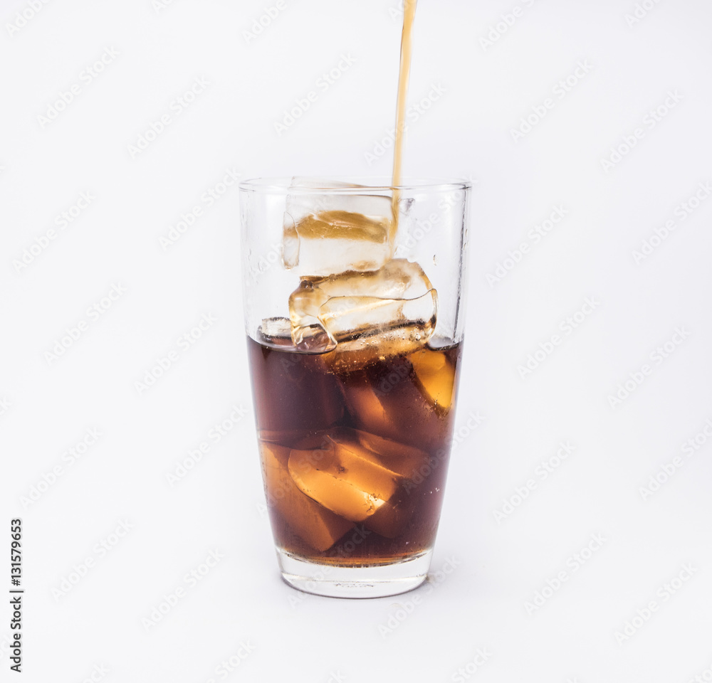 soft drink pouring from a plastic bottle into a glass filled with ice cubes and half cola soft drink pouring from a plastic bottle into a glass filled with ice cubes and half cola