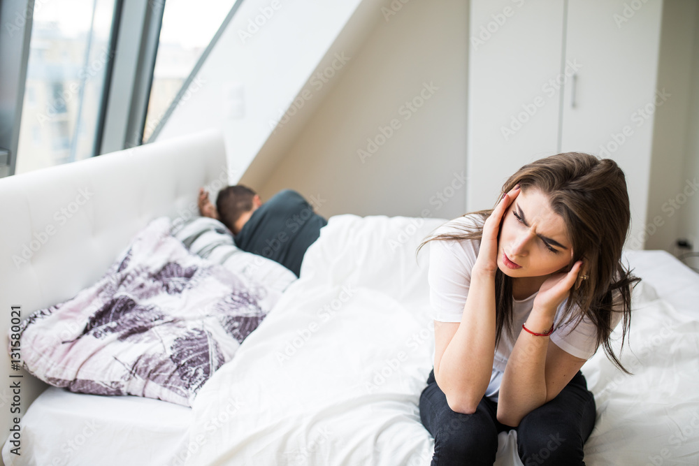 Portrait of unhappy young heterosexual couple in bedroom Portrait of unhappy young heterosexual couple in bedroom