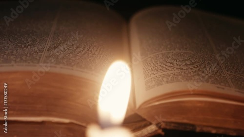 dolly shot of an open ancient book lit by candles