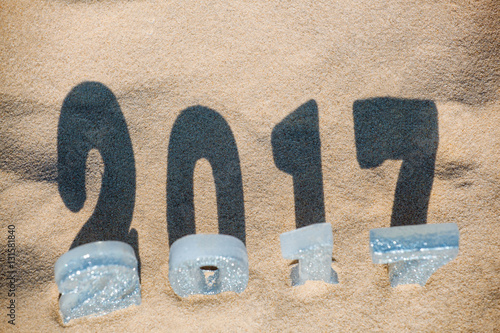 Four New Year's figures are in the sand on the beach or seaside cast a large shadow on the ground. New Year Celebration and Christmas in the ocean the sea. Traveling.