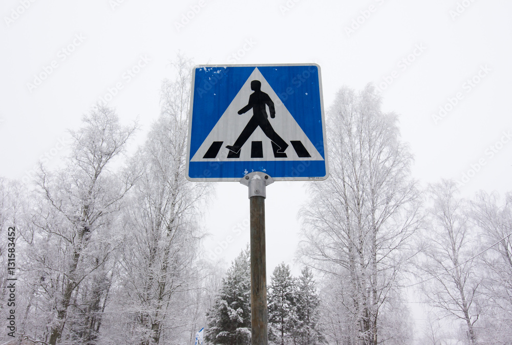 Pedestrian crossing road sign on winter sky background.