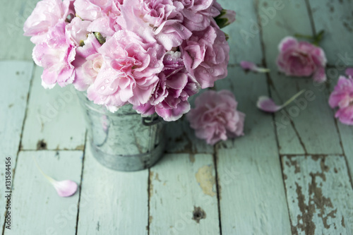 Pink carnation flowers in zinc bucket on vintage wood