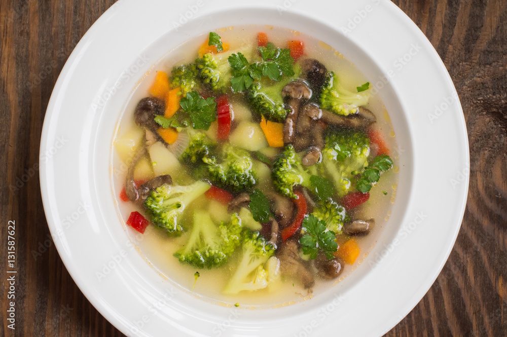 Vegetable soup with broccoli, mushrooms and herbs. Wooden background. Top view. Close-up Vegetable soup with broccoli, mushrooms and herbs. Wooden background. Top view. Close-up