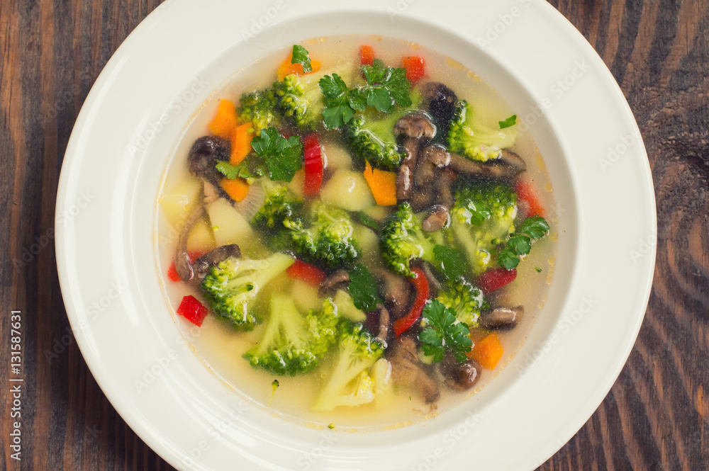 Vegetable soup with broccoli, mushrooms and herbs. Wooden background. Top view. Close-up Vegetable soup with broccoli, mushrooms and herbs. Wooden background. Top view. Close-up