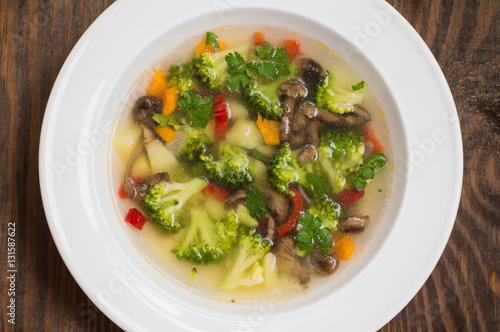 Vegetable soup with broccoli, mushrooms and herbs. Wooden background. Top view. Close-up