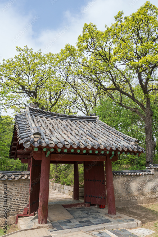 Verdant trees, wooden gate and stone wall next to the Jeongjeon - the main hall of the Jongmyo Shrine in Seoul, South Korea. Verdant trees, wooden gate and stone wall next to the Jeongjeon - the main hall of the Jongmyo Shrine in Seoul, South Korea.