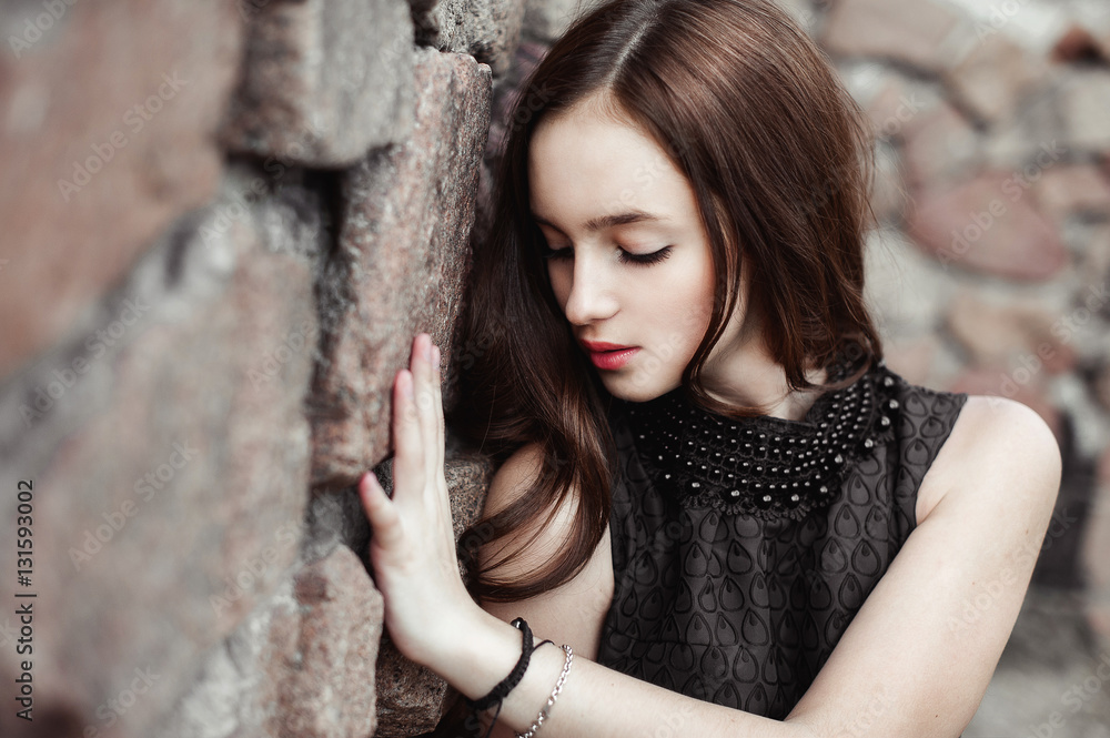 Fototapeta premium beautiful sad young woman on a stone wall background