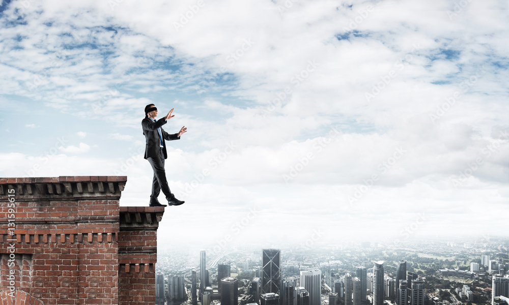 Danger and risk concept with businessman making step from edge Danger and risk concept with businessman making step from edge
