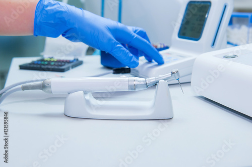 Assistant s hands configures dental equipment in dentist s office. Close up  selective focus. Dentistry