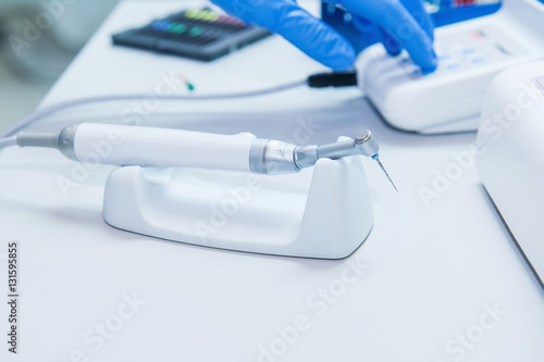Assistant's hands configures dental equipment in dentist's office. Close up, selective focus. Dentistry