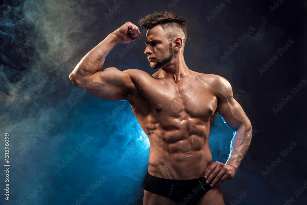Handsome power athletic man bodybuilder. Wet Fitness muscular body on dark  smoke background. Perfect male. Awesome bodybuilder, posing. Stock Photo |  Adobe Stock