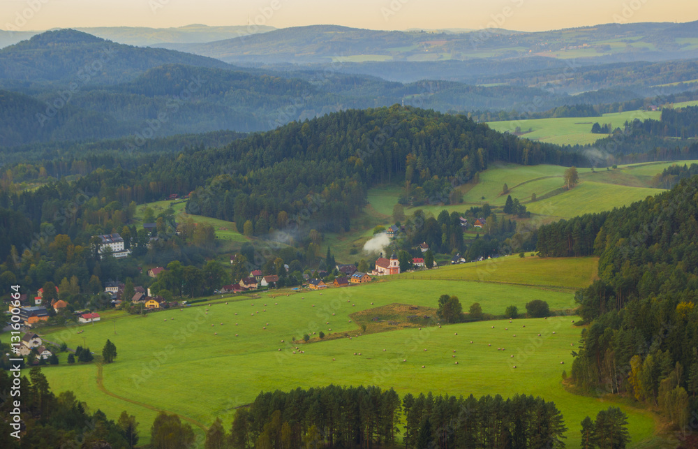 Hills and villages with foggy morning. Morning fall valley of Bohemian Switzerland park. 
