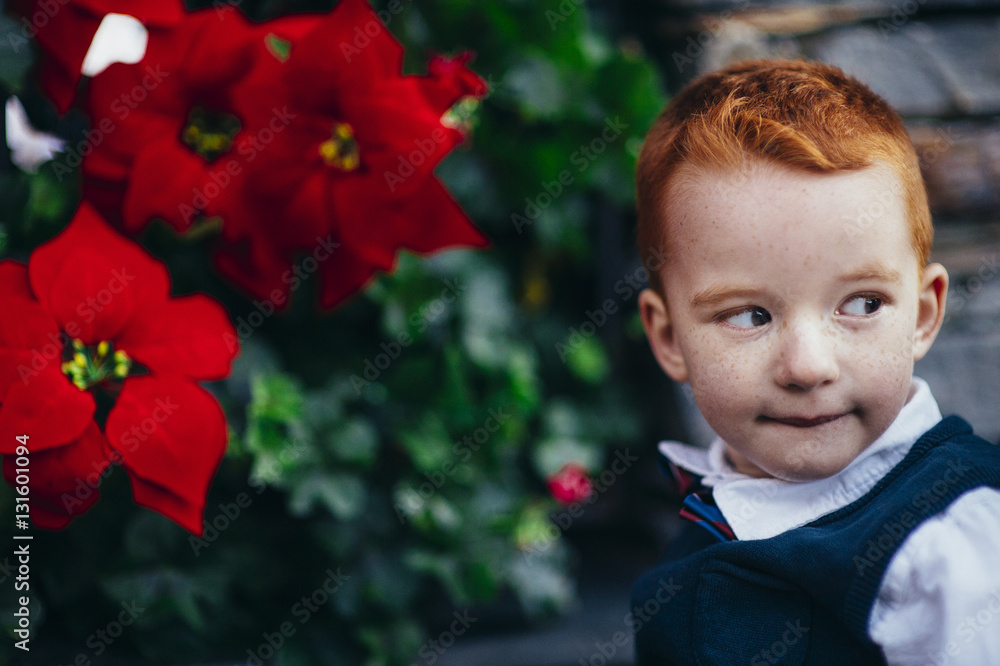 Child with red hair and freckles next to flowers Child with red hair and freckles next to flowers