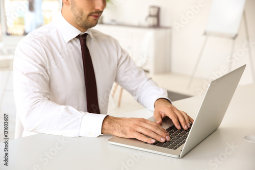 Male hands typing on laptop at office