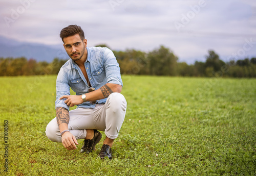 Obraz na plátne Handsome young man at countryside, in front of field or grassland, wearing shirt