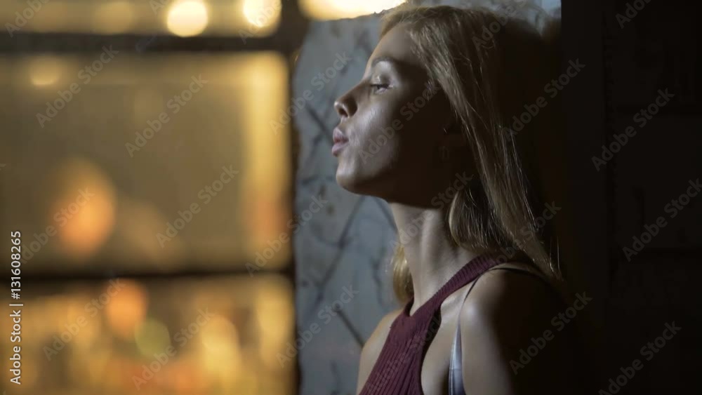 Sexy blonde woman standing near night club and smoking a cigarette, relaxation Sexy blonde woman standing near night club and smoking a cigarette, relaxation