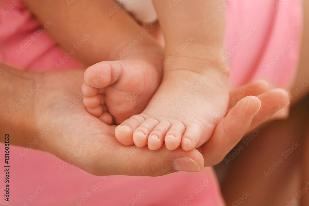 Woman hand holding bare baby feet, close up view Woman hand holding bare baby feet, close up view