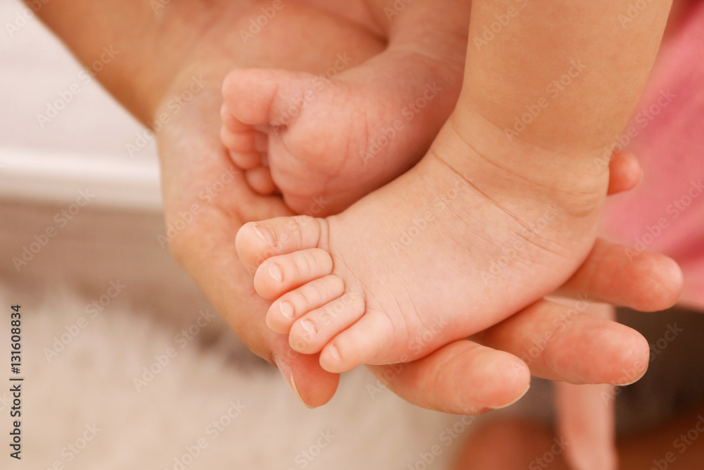 Woman hand holding bare baby feet, close up view Woman hand holding bare baby feet, close up view