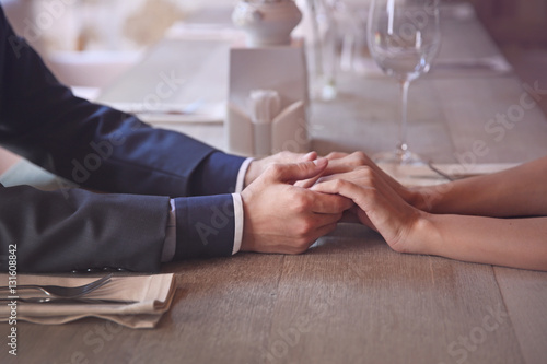 Man and woman holding hands together at restaurant  closeup