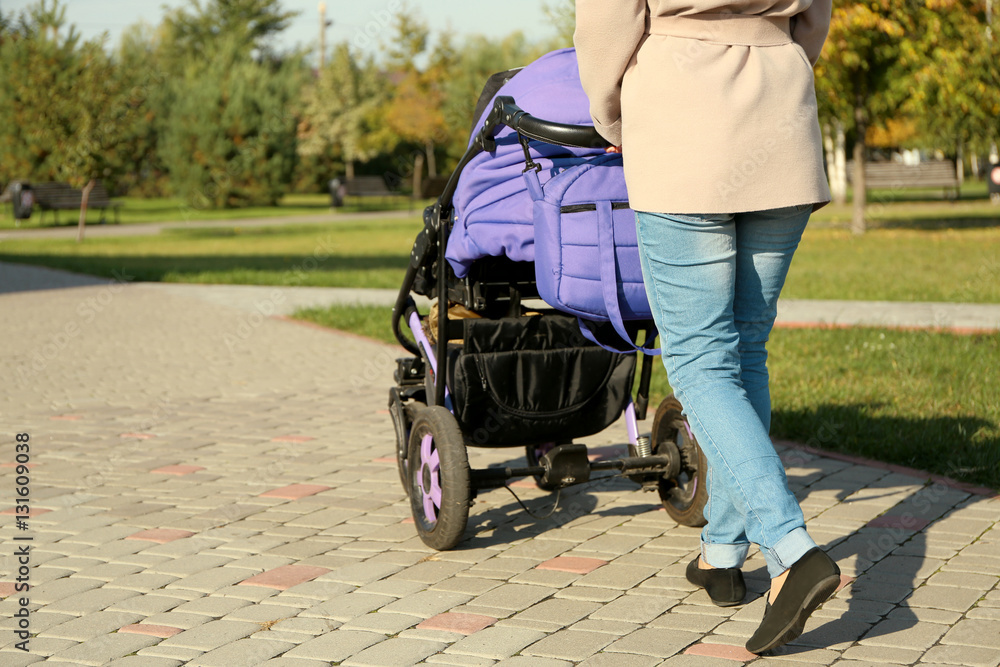 Obraz premium Woman with baby stroller walking in green park