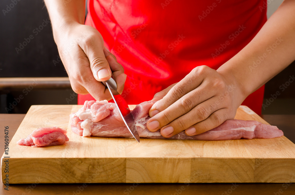 Chef cutting raw pork on wooden board prepared for cooking