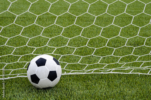 The soccer football with the net on the artificial green grass soccer field