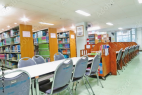 Blurred of interior of old library with bookshelf , tables and chairs.