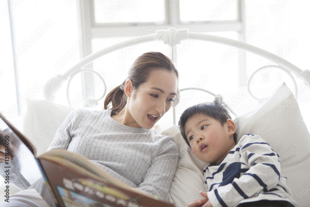 Mother is showing her picture book to her son in bed Mother is showing her picture book to her son in bed