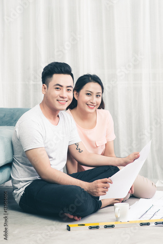 Attractive young asian adult couple looking at house plans.