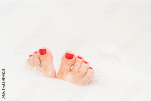 Feet with red nails soaking in spa bath