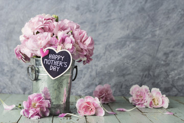Pink carnation flowers in zinc bucket with happy mothers day let