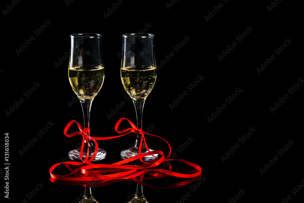 two glasses with champagne and red ribbon on black background two glasses with champagne and red ribbon on black background