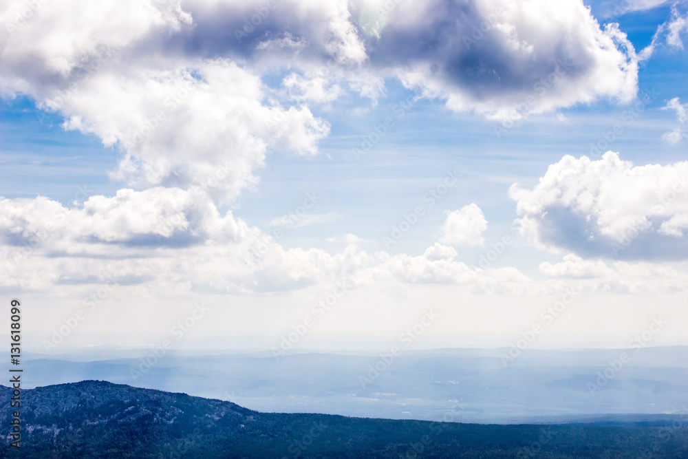 Blue mountains and clouds above view from airplane.High mountain landscape in haze Blue mountains and clouds above view from airplane.High mountain landscape in haze