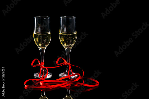 two glasses with champagne and red ribbon on black background