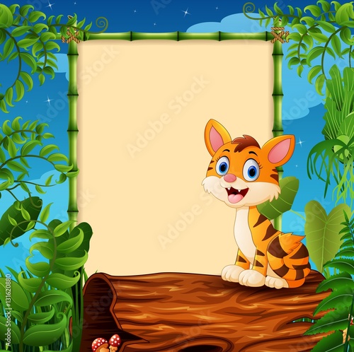 Fototapeta Naklejka Na Ścianę i Meble -  Cartoon tiger sitting on hollow log near the empty framed signboard