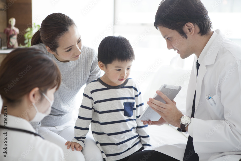 The doctor explains it while showing the tablet to parent and child The doctor explains it while showing the tablet to parent and child